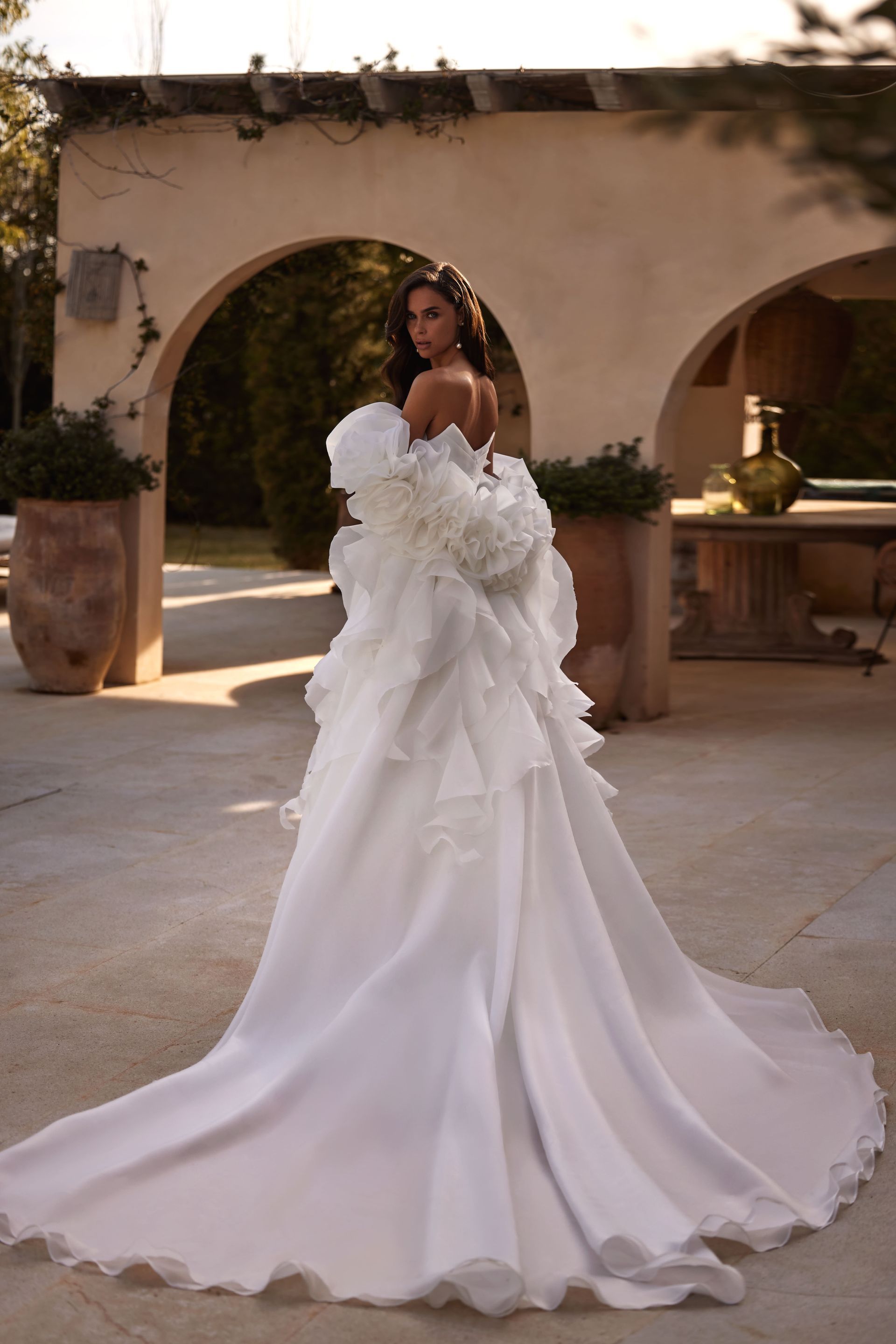 Eine Frau in einem weißen Brautkleid steht vor einem Gebäude.