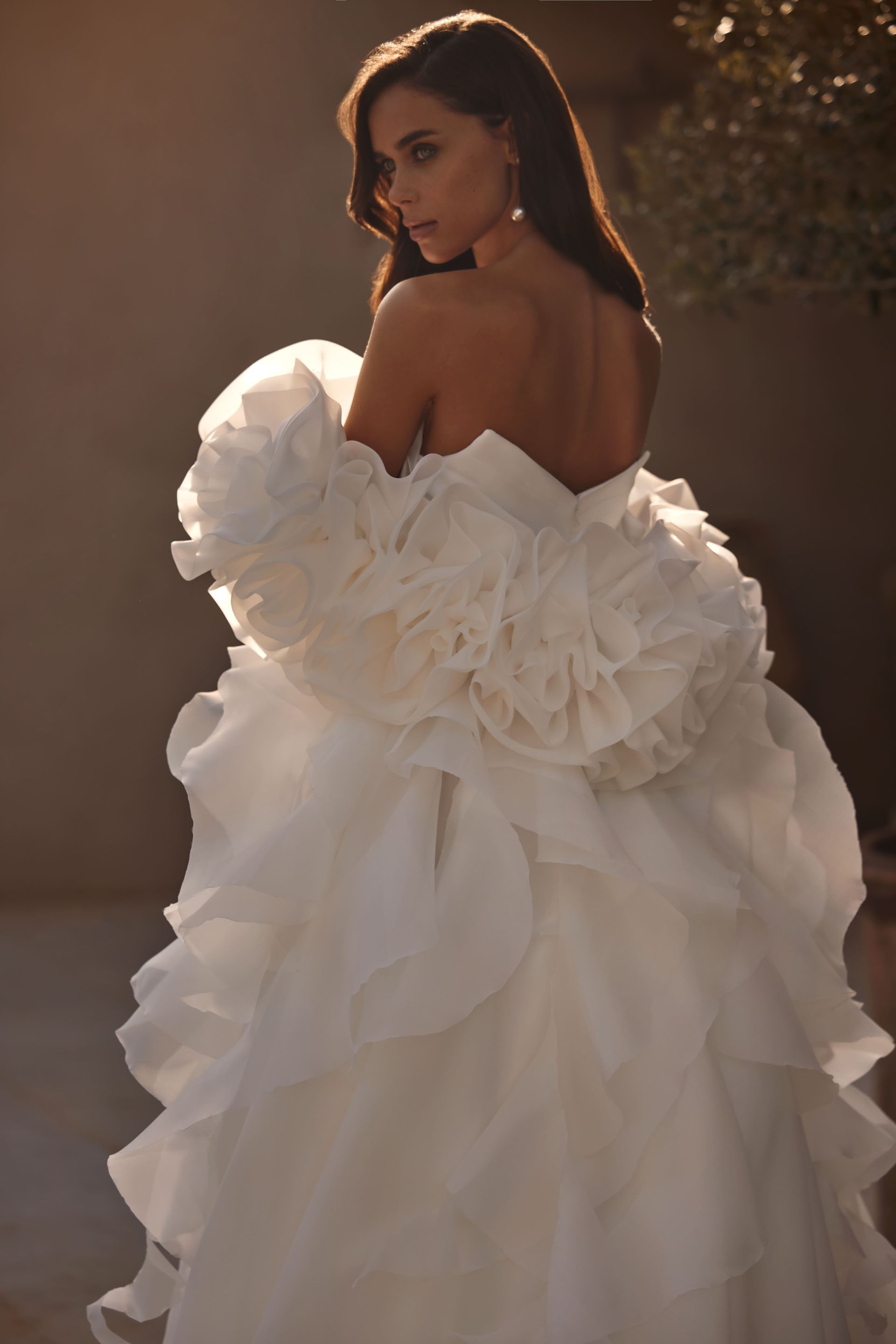 Der Rücken einer Frau in einem weißen Brautkleid mit Rüschen.