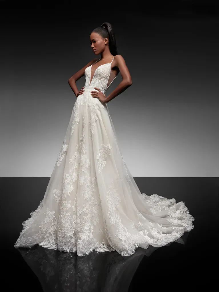 Eine Frau in einem weißen Brautkleid steht mit den Händen in den Hüften da.