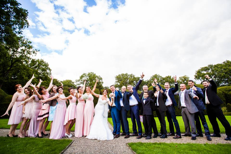 Eine große Gruppe von Menschen posiert bei einer Hochzeit für ein Foto.