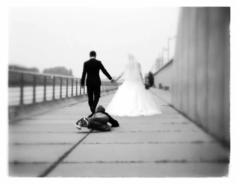 Ein Schwarzweißfoto einer Braut und eines Bräutigams, die über eine Brücke gehen