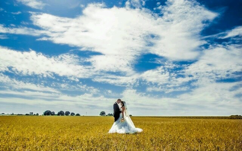 Eine Braut und ein Bräutigam küssen sich in einem Weizenfeld.