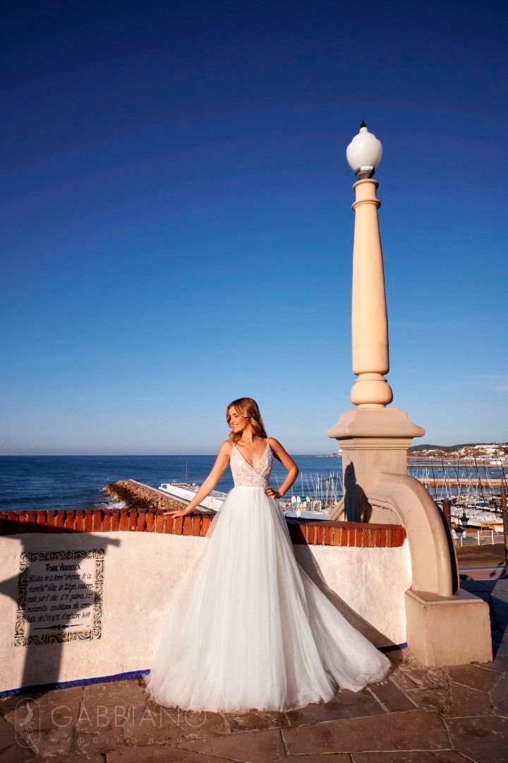 Eine Frau in einem Brautkleid steht auf einem Balkon mit Blick auf das Meer.