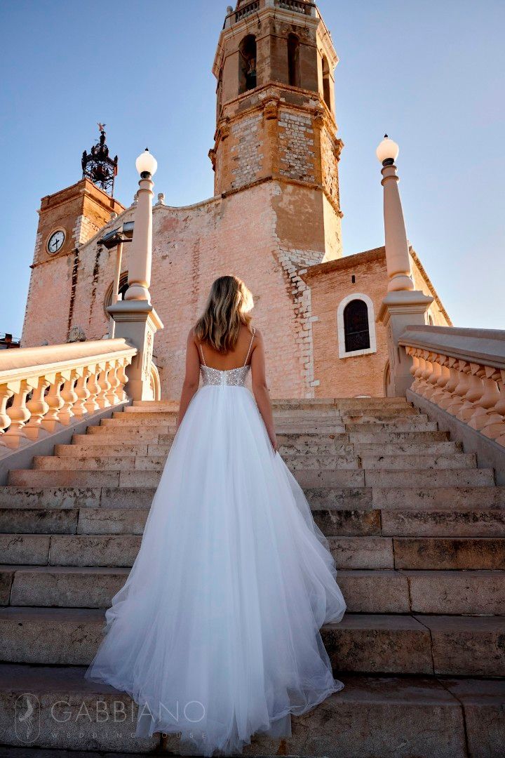 Eine Frau in einem Brautkleid steht auf einer Treppe vor einer Kirche.