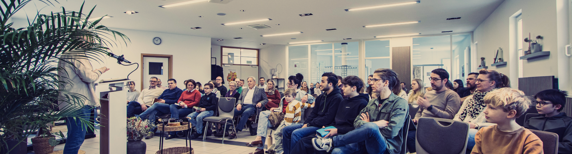 Gemeindesaal mit Klavier und Liederbuch im Vordergrund