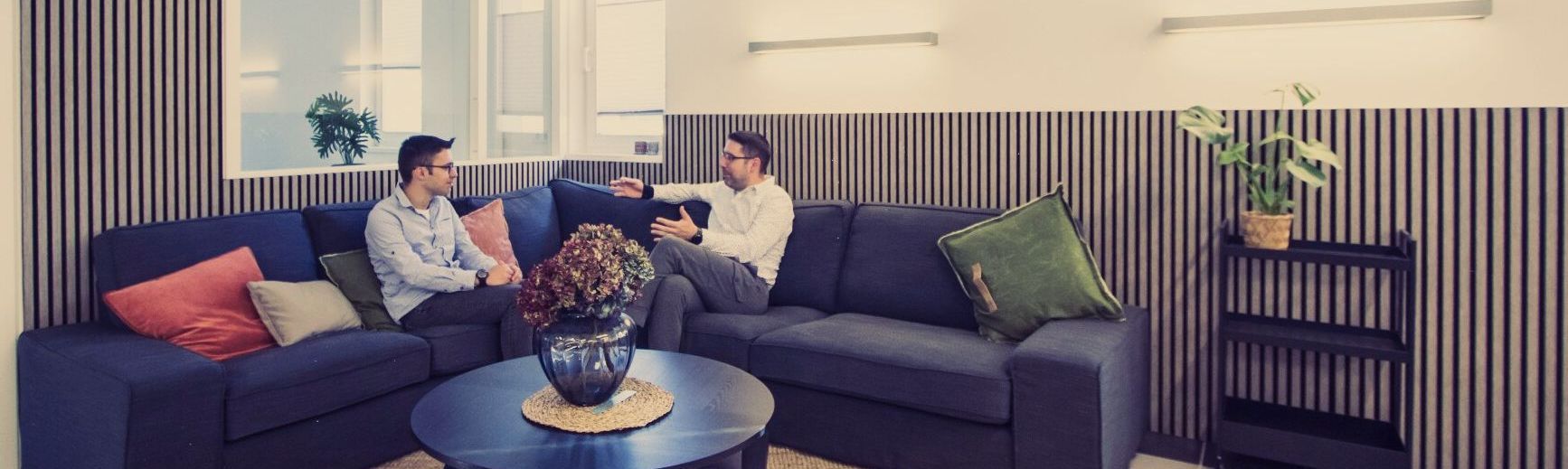 Gemeindesaal mit Sofaecke, zwei Menschen unterhalten sich