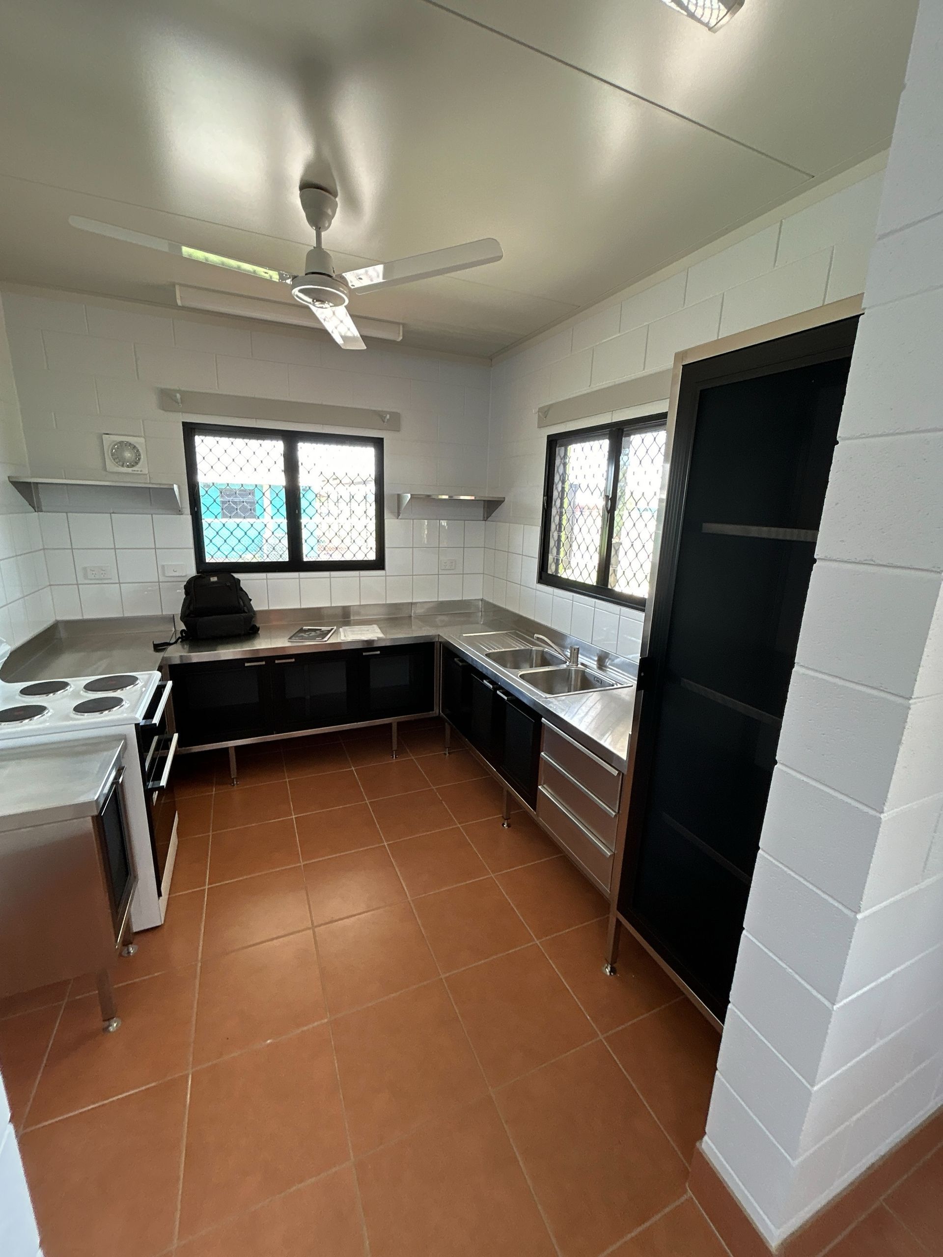A stainless steel kitchen with white tiles — Readycut Screens & Doors in Winnellie, NT