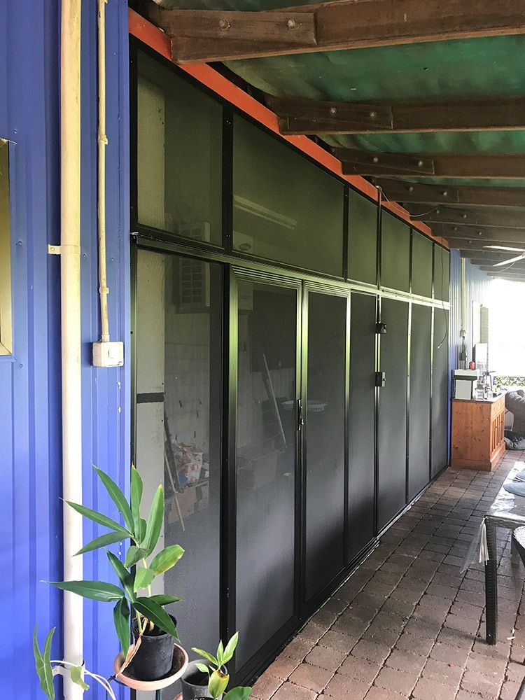 A Blue Building With Sliding Glass And Security Screen — Readycut Screens & Doors in Winnellie, NT
