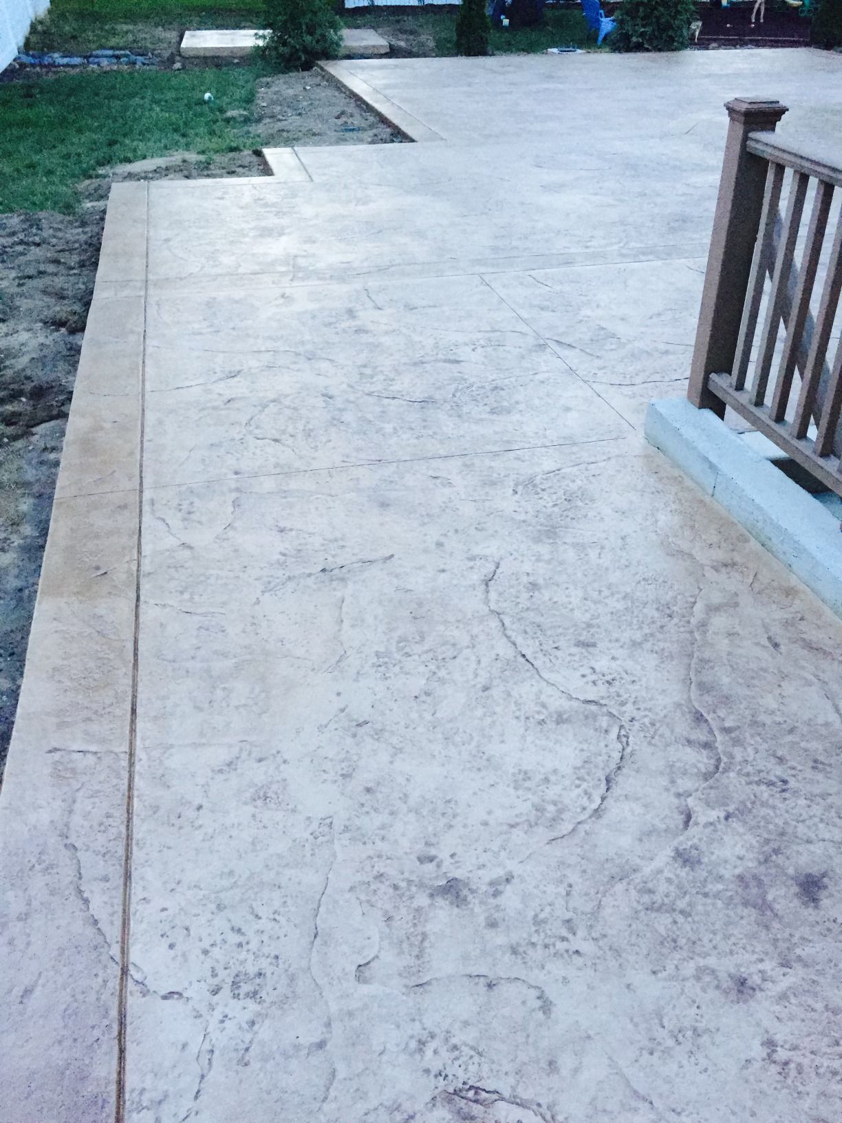 A concrete walkway with a wooden railing leading to a deck.