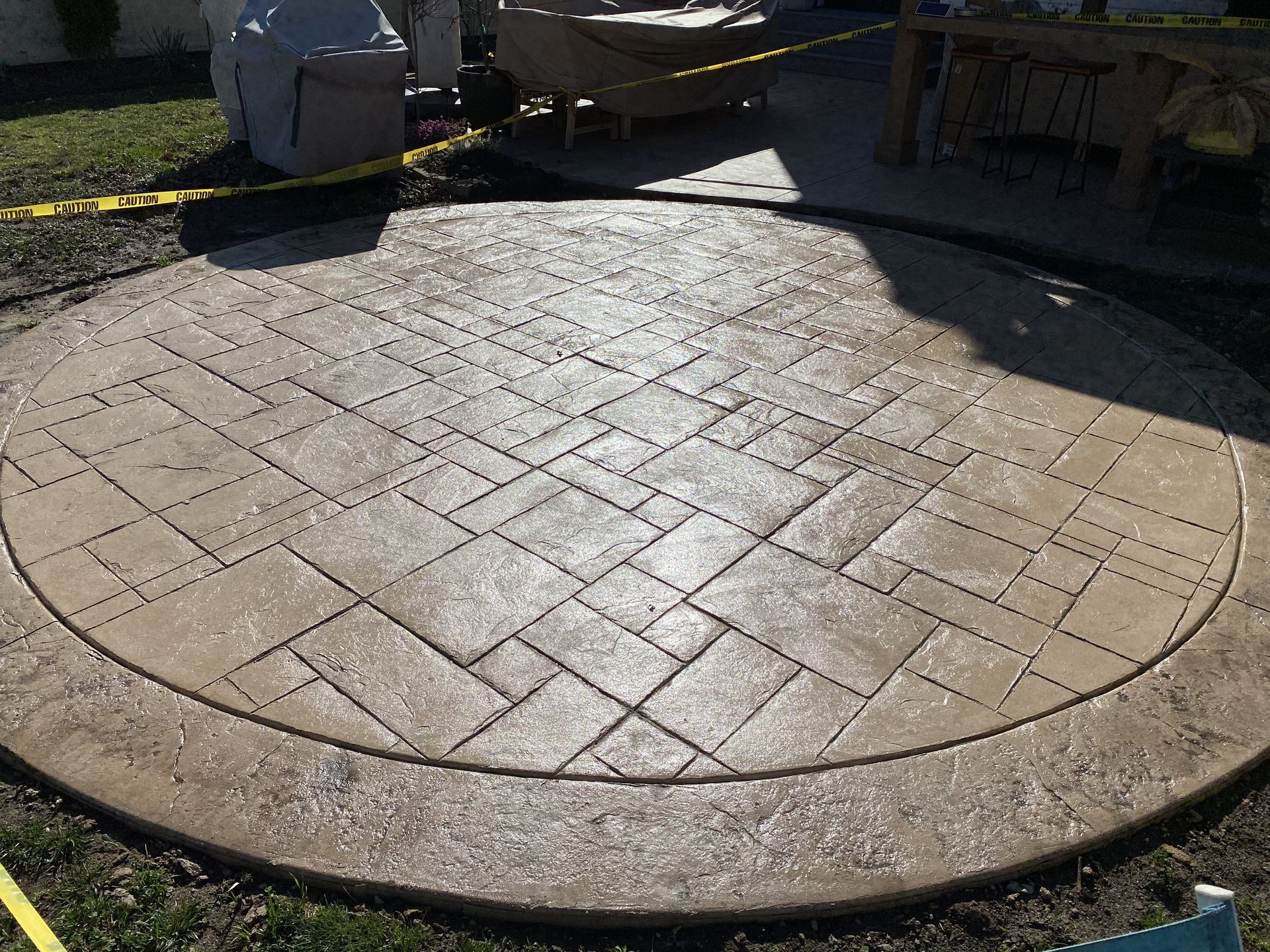 A circular concrete patio with a herringbone pattern