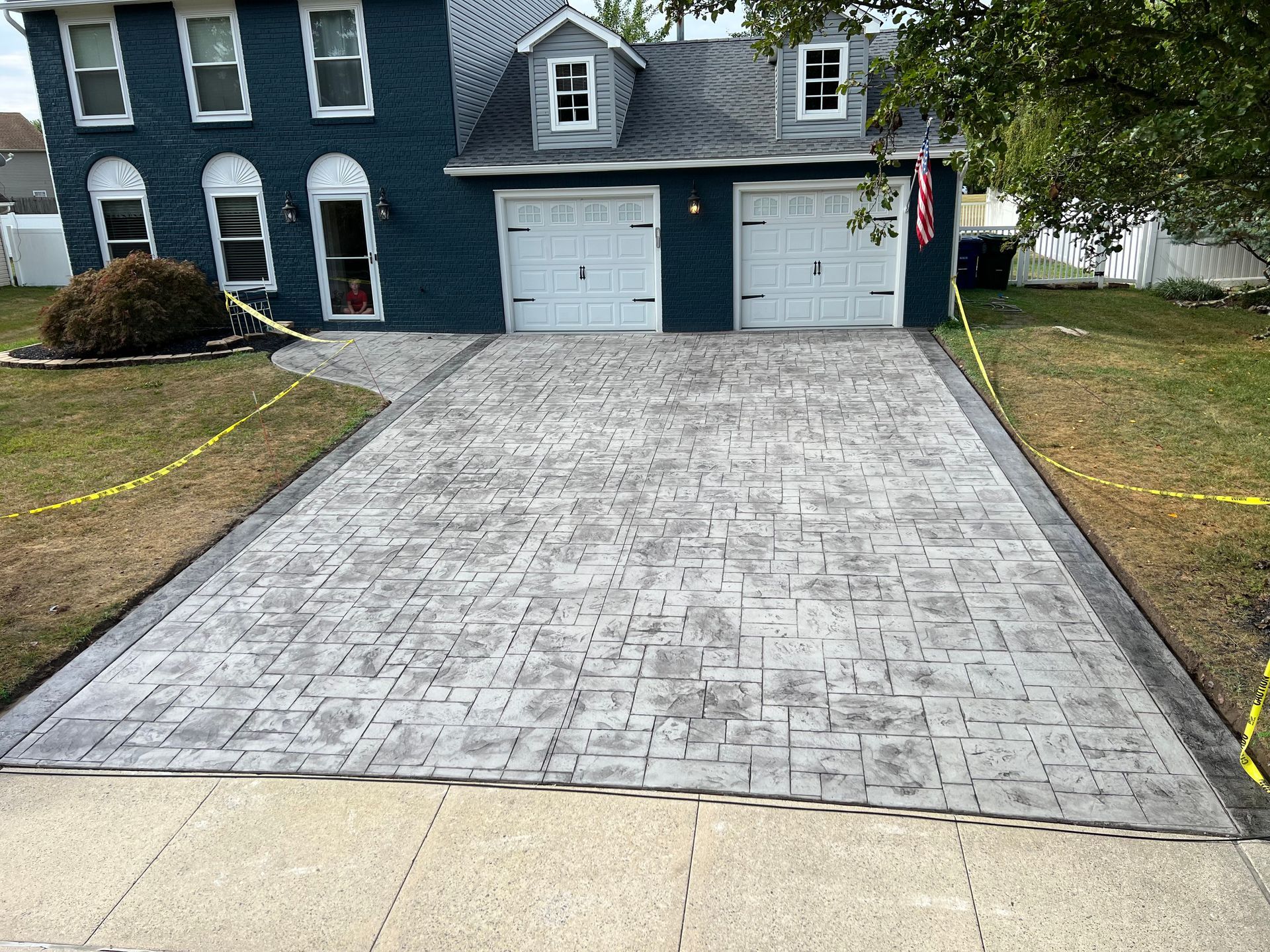 A brick driveway in front of a blue house.
