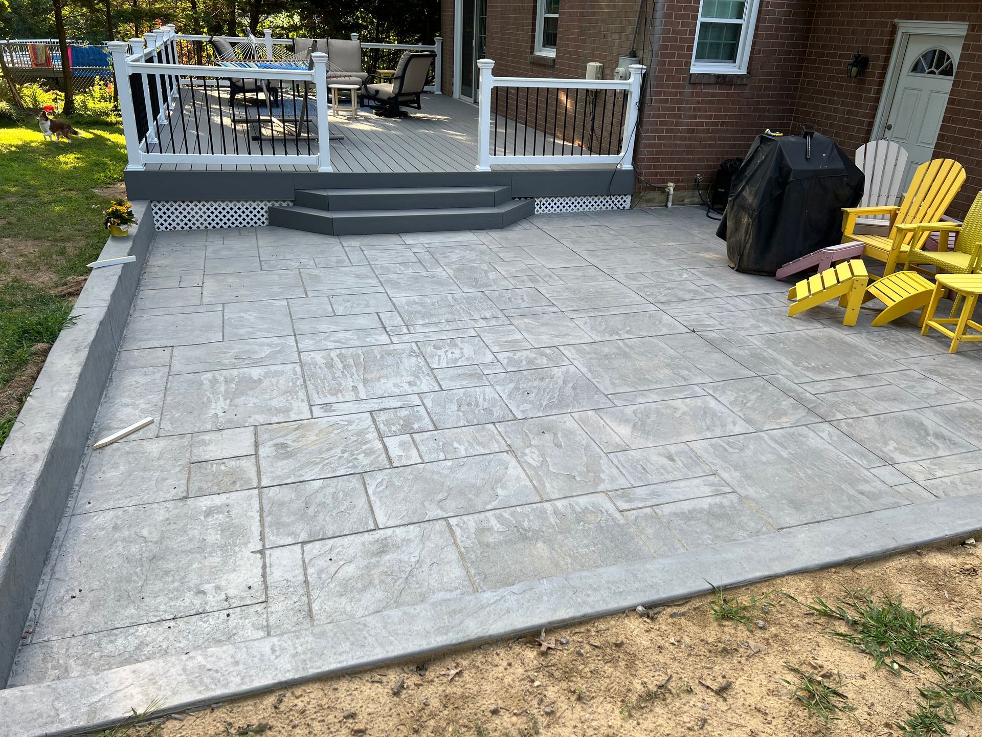 A patio with a deck and chairs in front of a house.