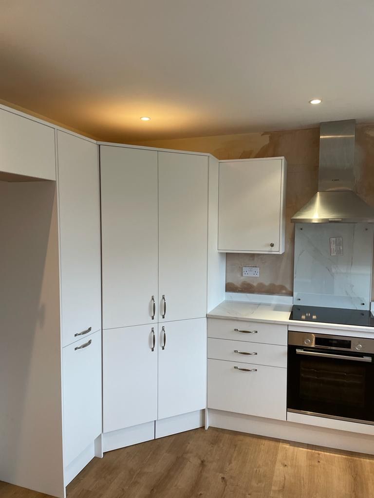 A kitchen with white cabinets and a stove top oven
