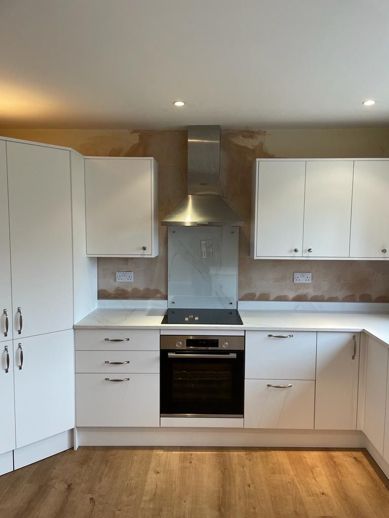 A kitchen with white cabinets and a stove top oven