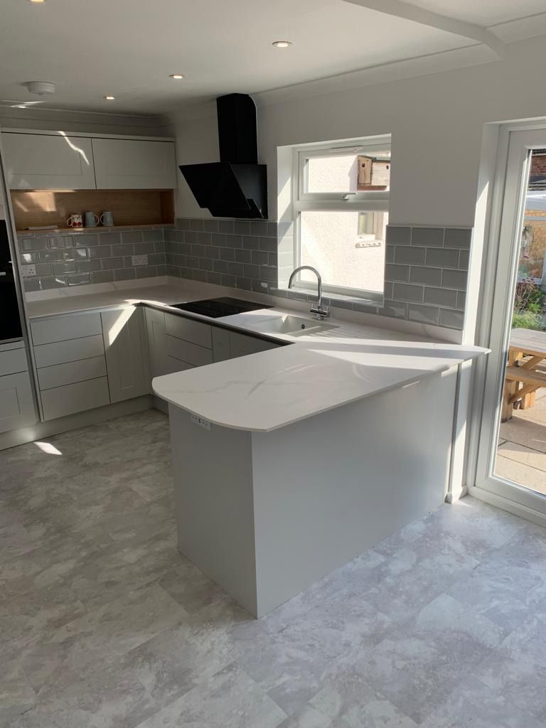 A kitchen with white cabinets , a sink , a stove and a window.