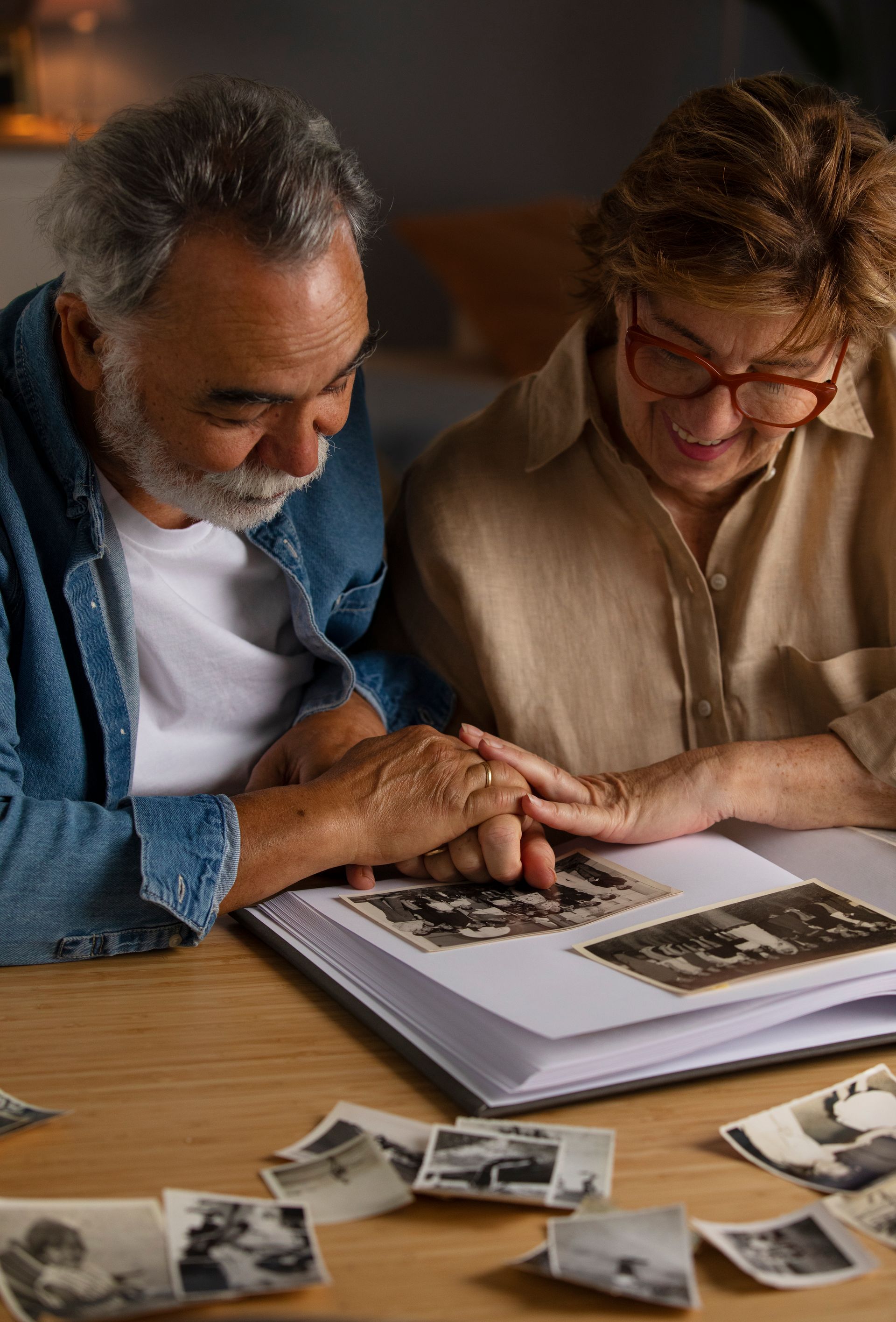 A man and a woman are sitting at a table looking at a photo album.