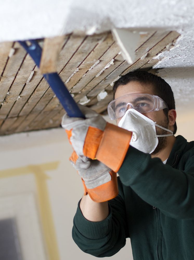 Man in Safety Gear, Removing Ceiling With Chisel and Hammer — Swift Pest Control in Ellalong, NSW