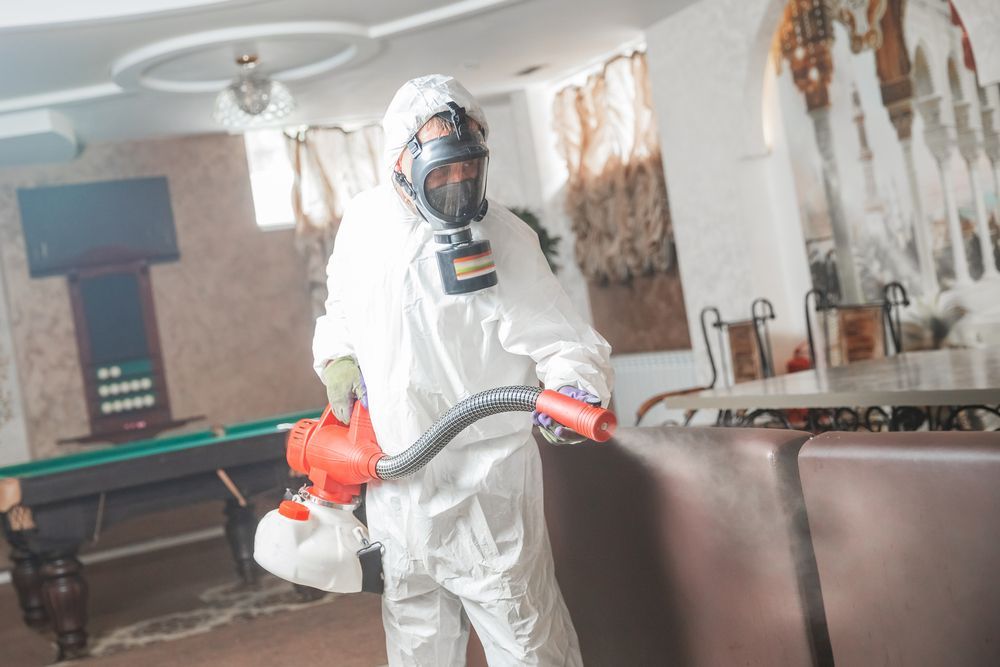 Person in Hazmat Suit Disinfecting a Room With a Fogger, Near a Pool Table — Swift Pest Control in Ellalong, NSW