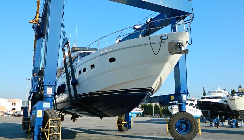 White Yacht Being Lifted by a Blue Boat Hoist — ASAP Batteries & Breakdowns in Burleigh Heads, QLD