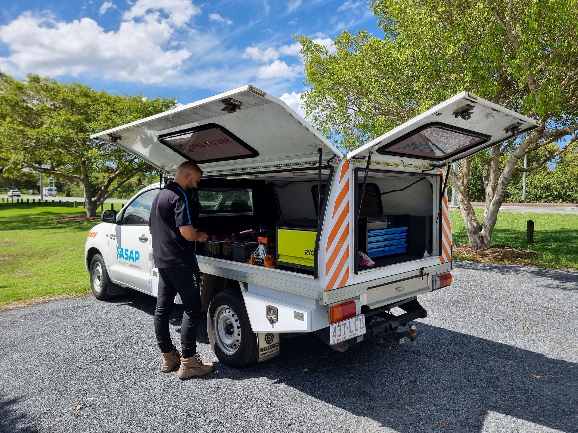 Man working from utility truck with open canopy. White truck with orange stripes parked on gravel. Sunny day. — ASAP Batteries & Breakdowns in Burleigh Heads, QLD
