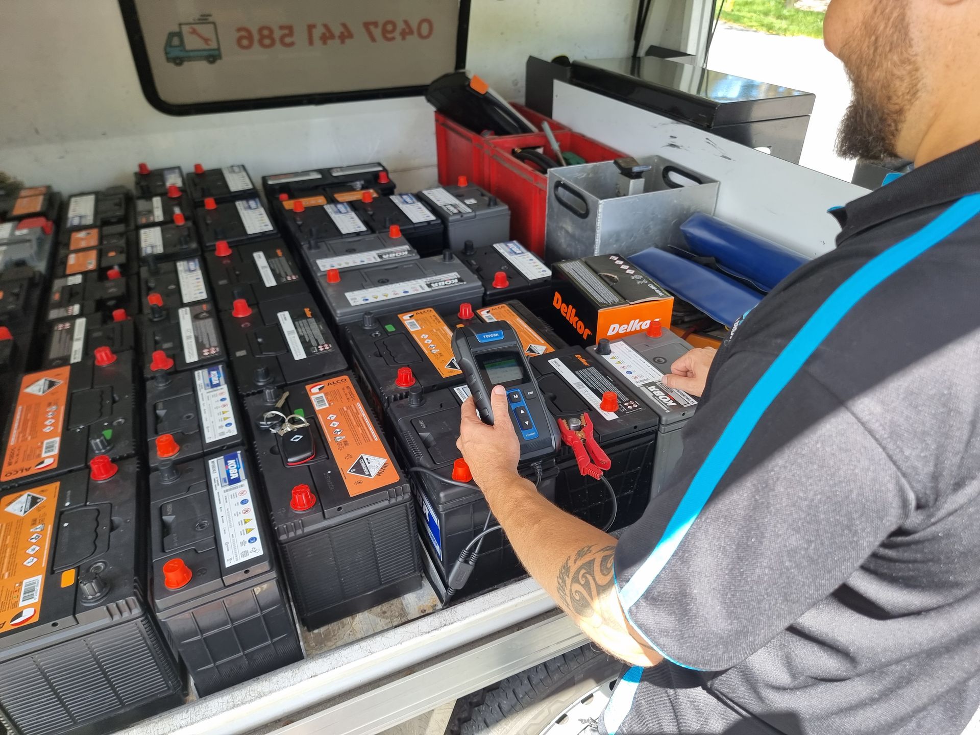 Person Testing Car Batteries in a Van. Many Batteries Are Arranged on a Shelf — ASAP Batteries & Breakdowns in Burleigh Heads, QLD