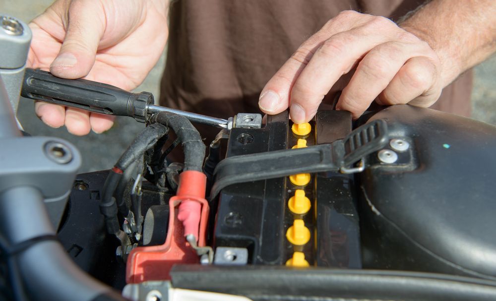 Hands Installing Motorcycle Battery, With Black Battery — ASAP Batteries & Breakdowns in Burleigh Heads, QLD