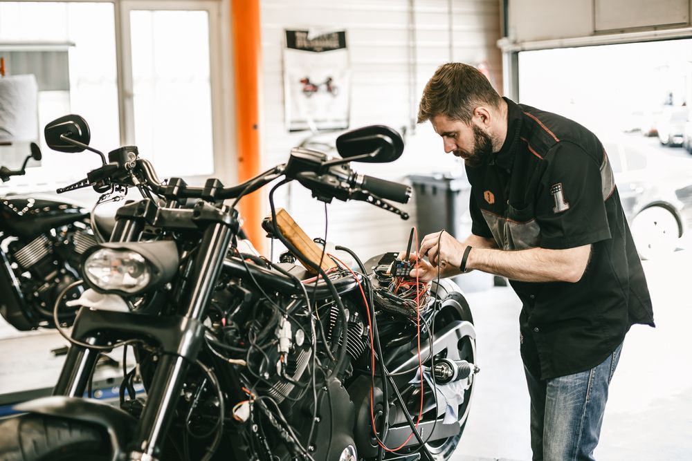 Mechanic Working on the Wiring of a Black Motorcycle — ASAP Batteries & Breakdowns in Burleigh Heads, QLD