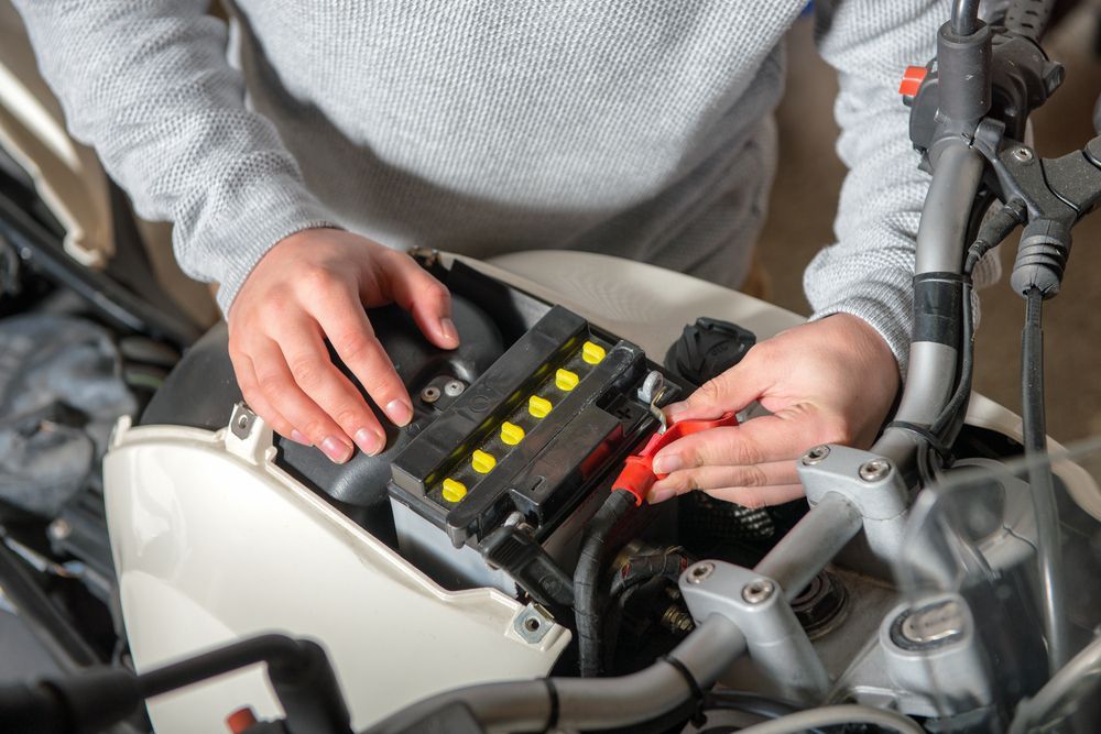 Hands in a Light Gray Sweater Connecting a Red Cable — ASAP Batteries & Breakdowns in Nerang, QLD