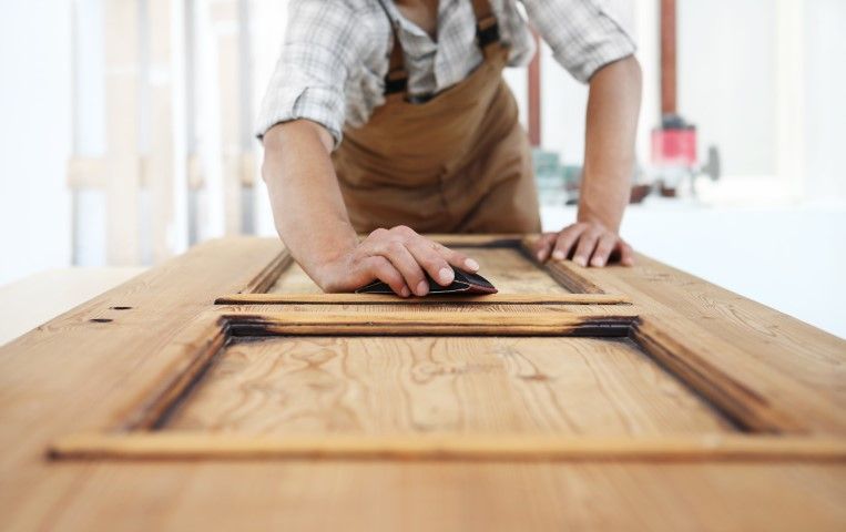 Person sanding wooden door frame.