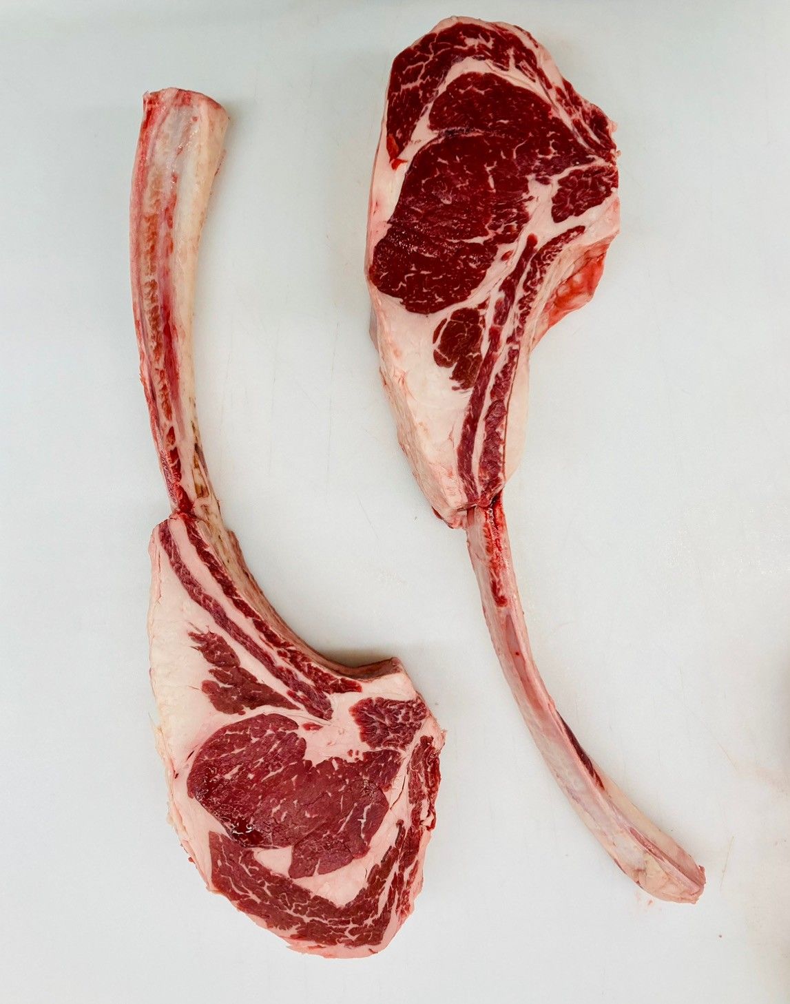 Two pieces of raw meat on a white surface