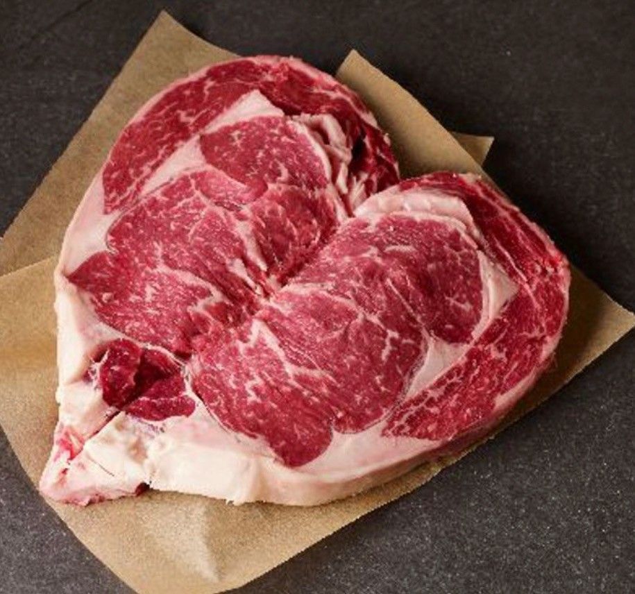 A heart shaped steak is sitting on a piece of brown paper