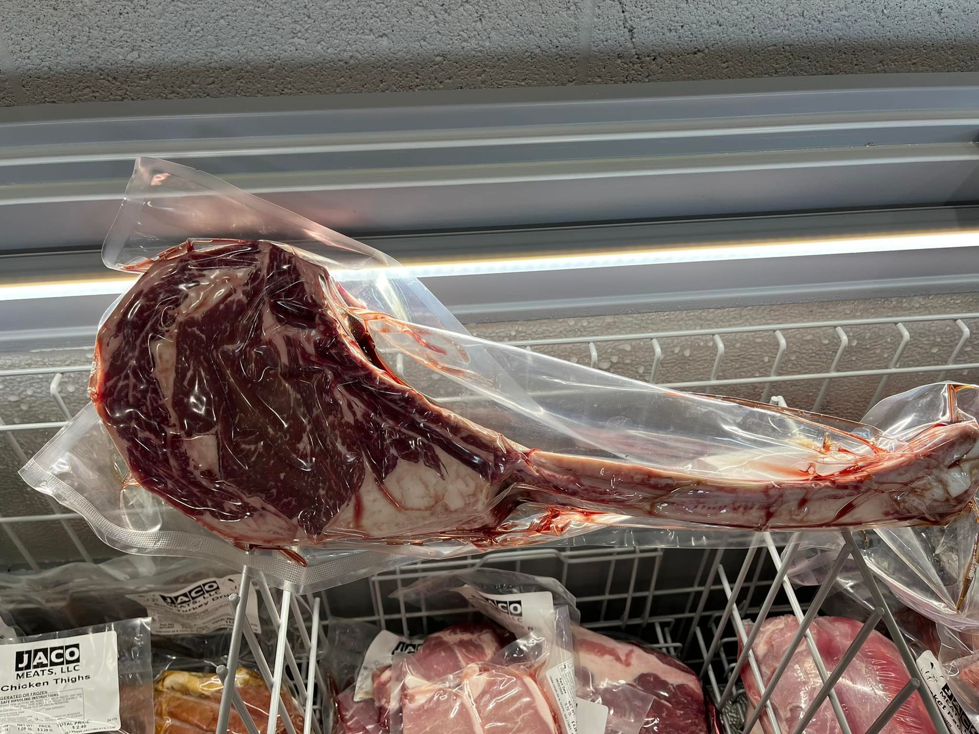A large piece of meat is sitting in a plastic bag in a freezer.