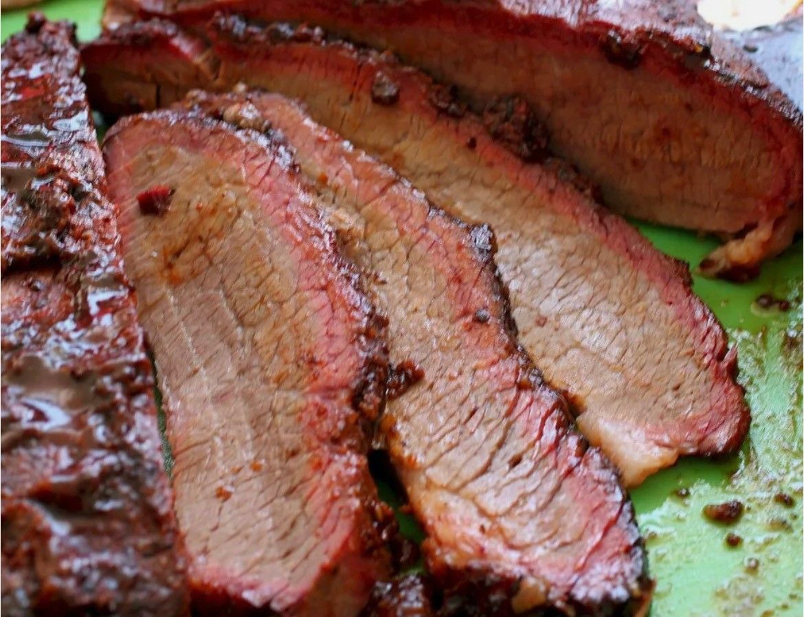 A close up of sliced brisket on a green cutting board.