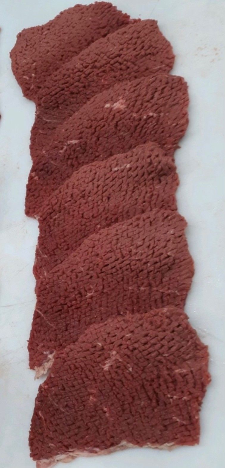 A bunch of pieces of meat are stacked on top of each other on a white surface.