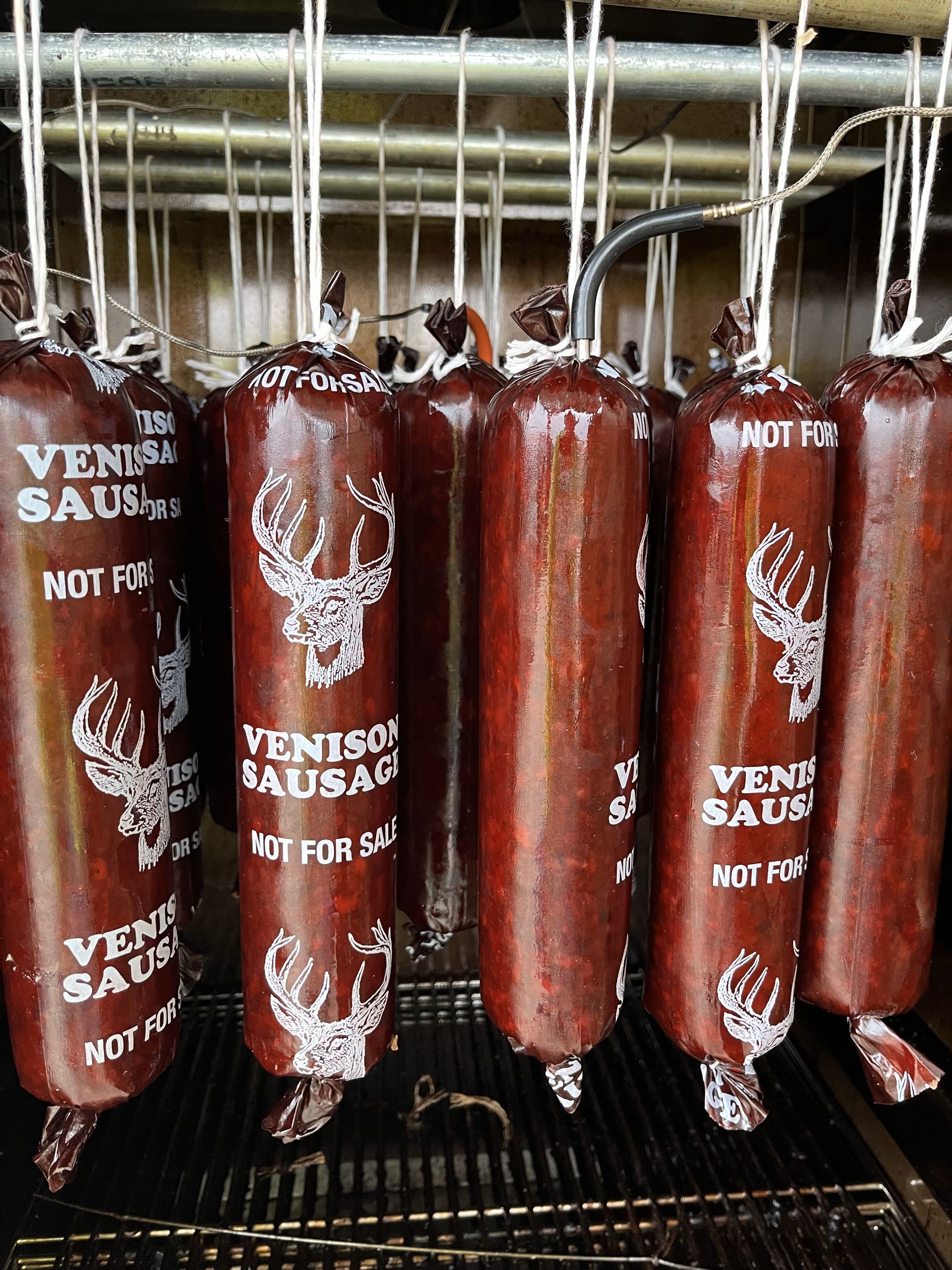 A bunch of venison sausages are hanging on a rack.