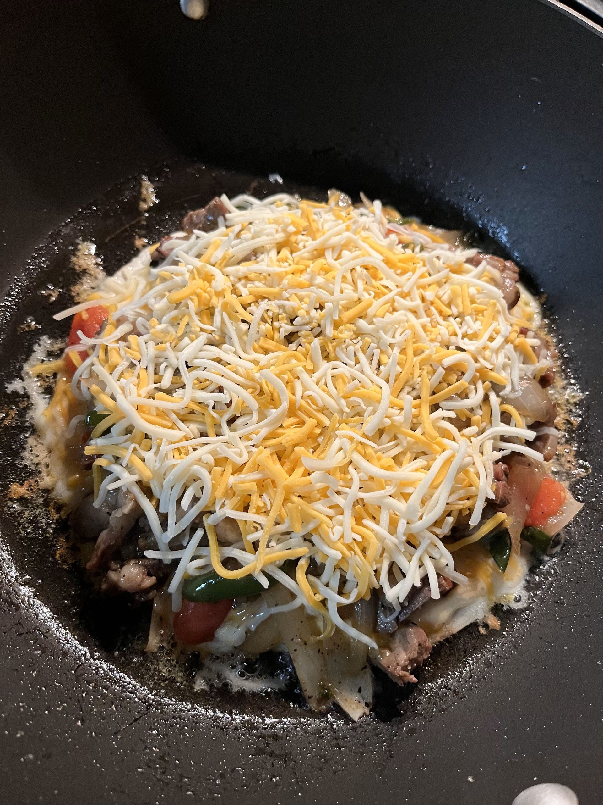 A pan filled with vegetables and cheese is being cooked.
