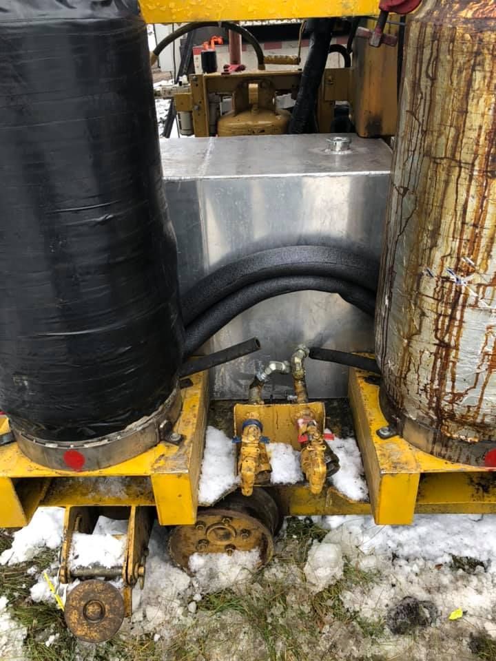 Deux bouteilles de gaz sont posées sur un chariot jaune dans la neige.