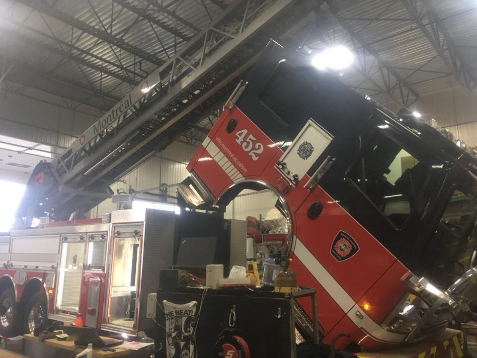 Un camion de pompiers portant le numéro 452 sur le côté est en réparation dans un garage.