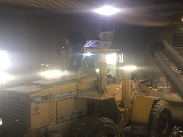 Un tracteur Volvo jaune est garé dans un garage la nuit.