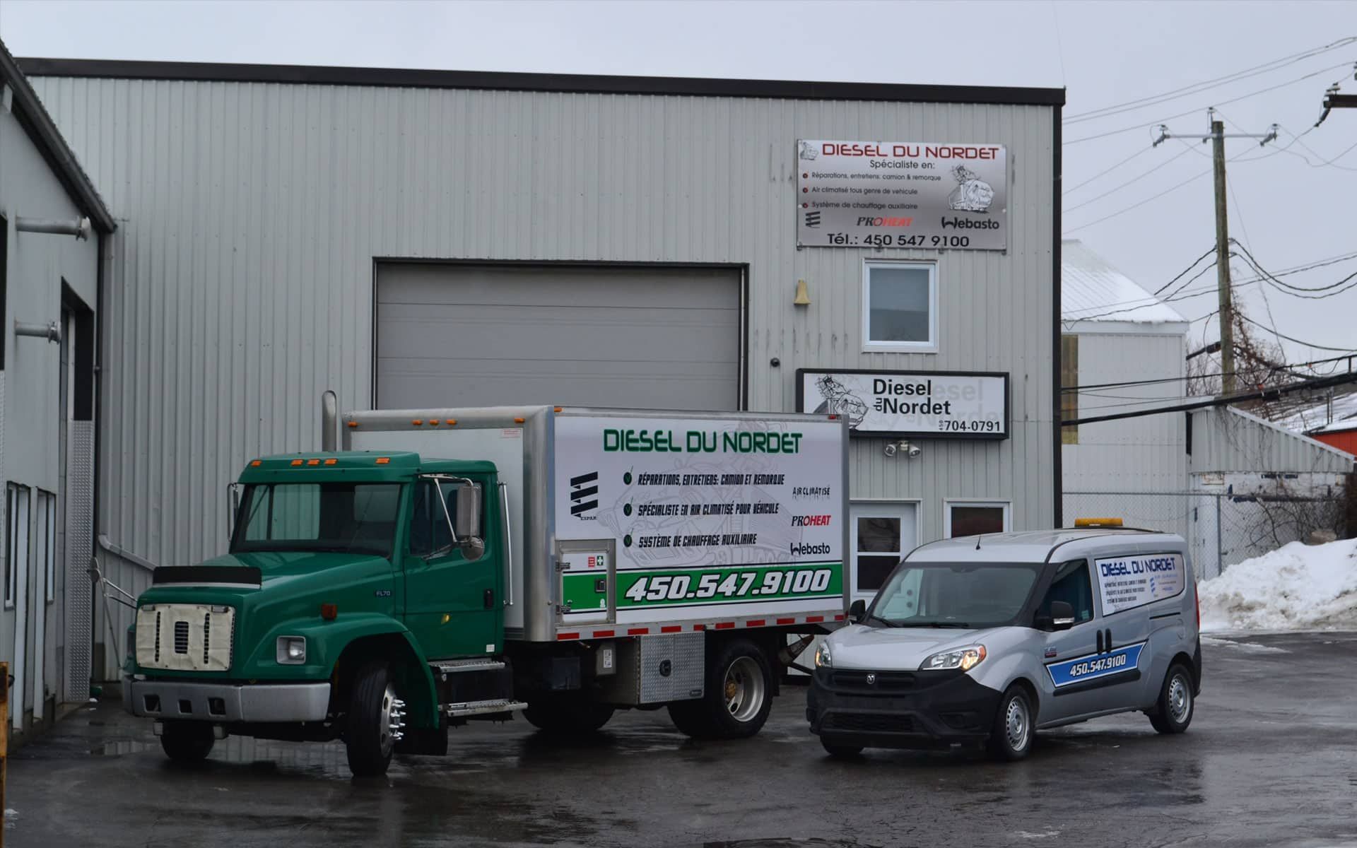 Un camion vert et une camionnette blanche sont garés devant un immeuble