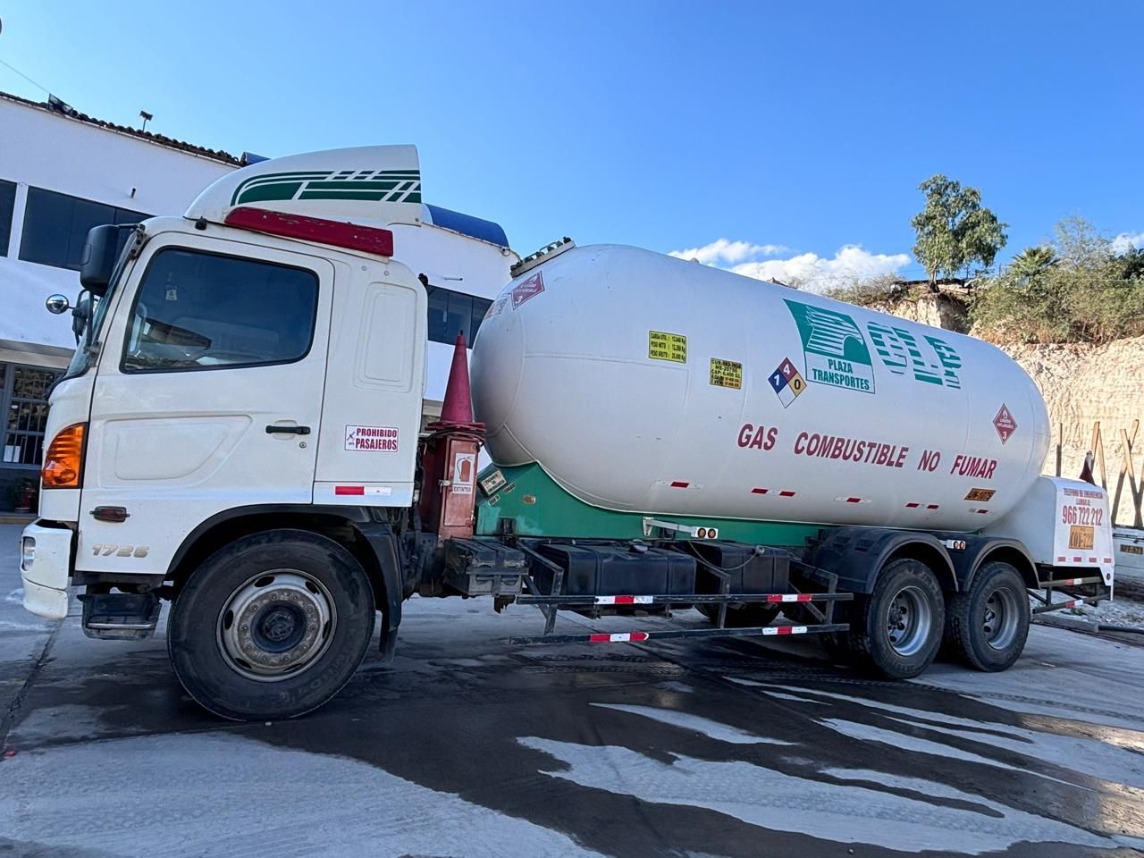 Camión cisterna blanco con un gran tanque de gasolina, estacionado al aire libre.