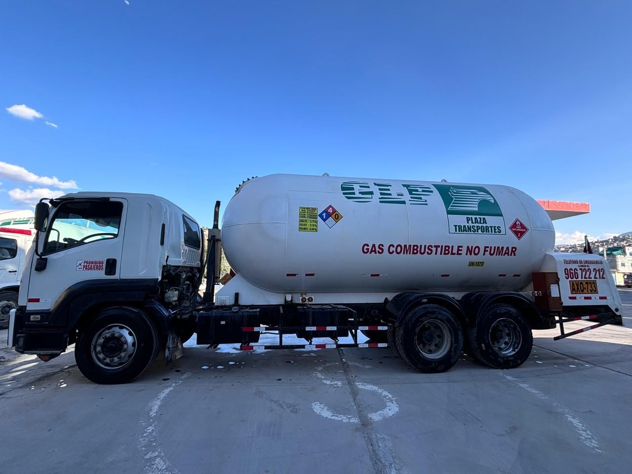 Camión cisterna blanco con un gran tanque, estacionado al aire libre bajo un cielo azul. 