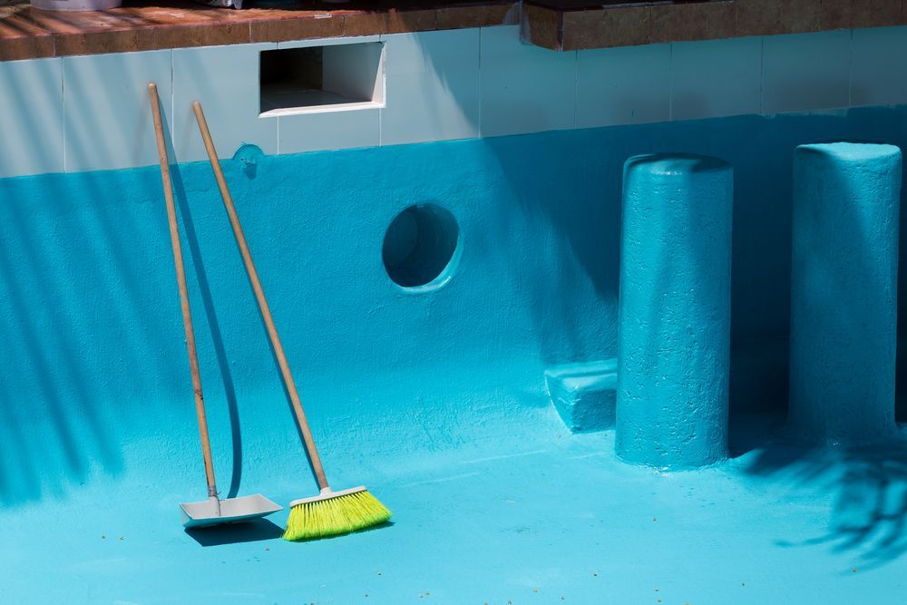 Empty, Blue Pool With Cleaning Brushes Resting Inside — Donna's Pool & Spa Centre In Port