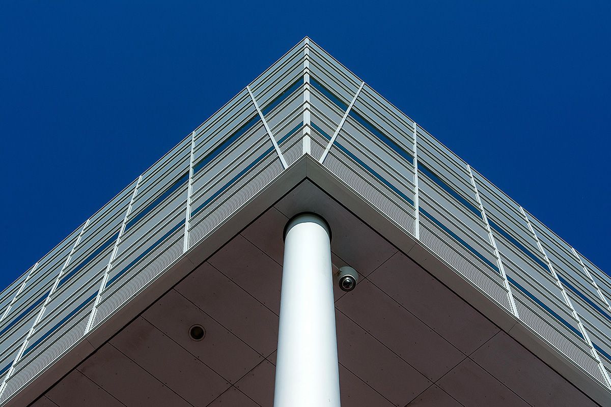 Low-angle view of a modern building corner with a white column and blue sky