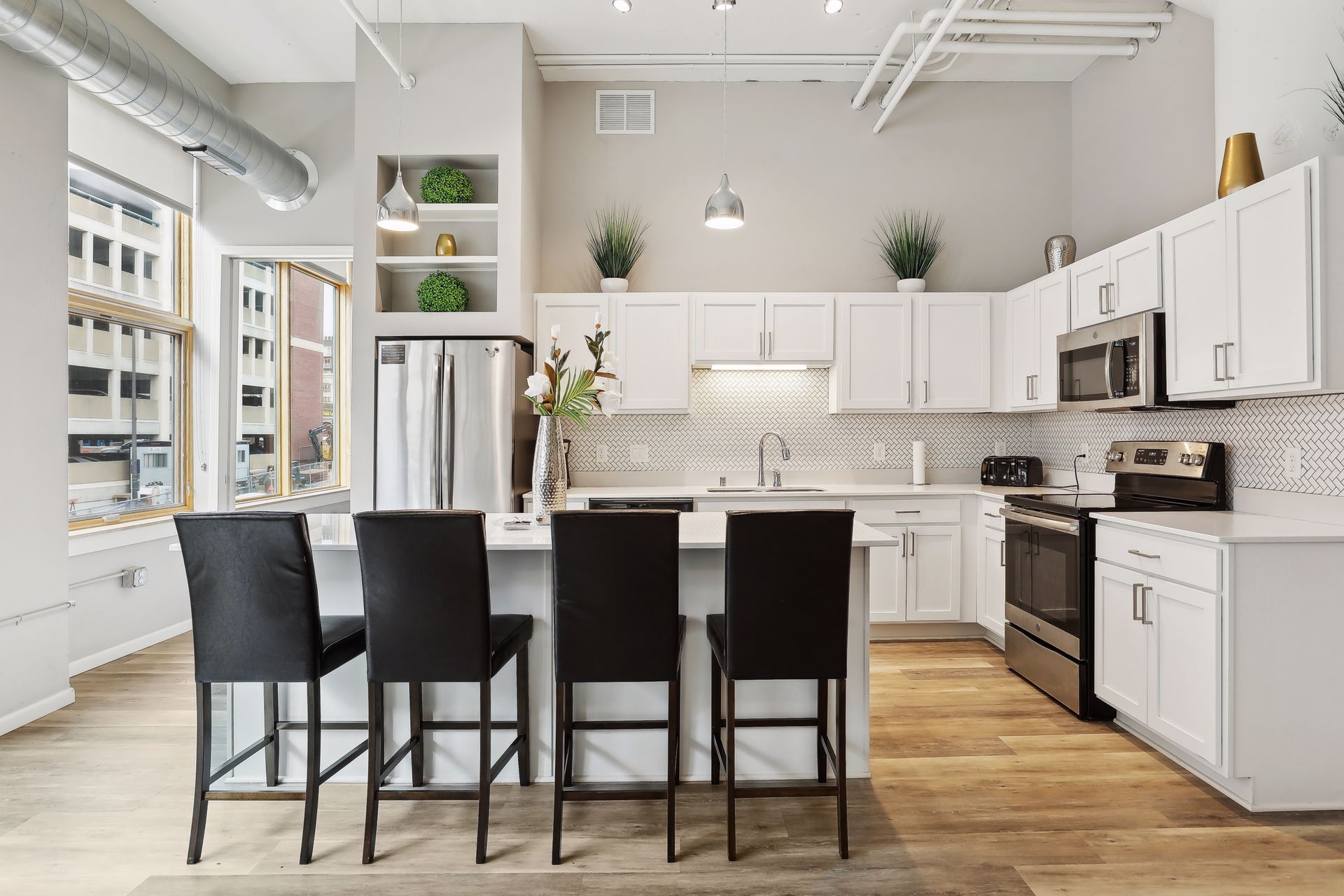 Modern kitchen with white cabinets, stainless steel appliances, and a central island with black bar stools.