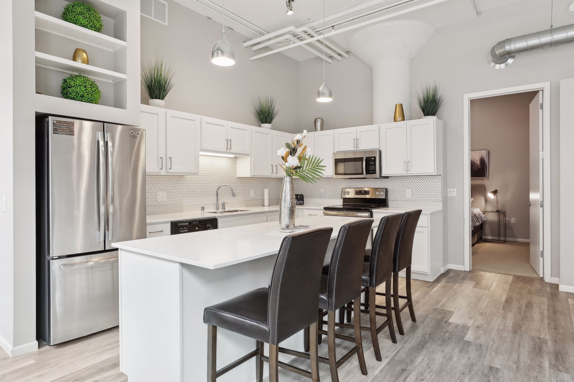 Modern kitchen with white cabinets, island with stools, and stainless steel appliances.