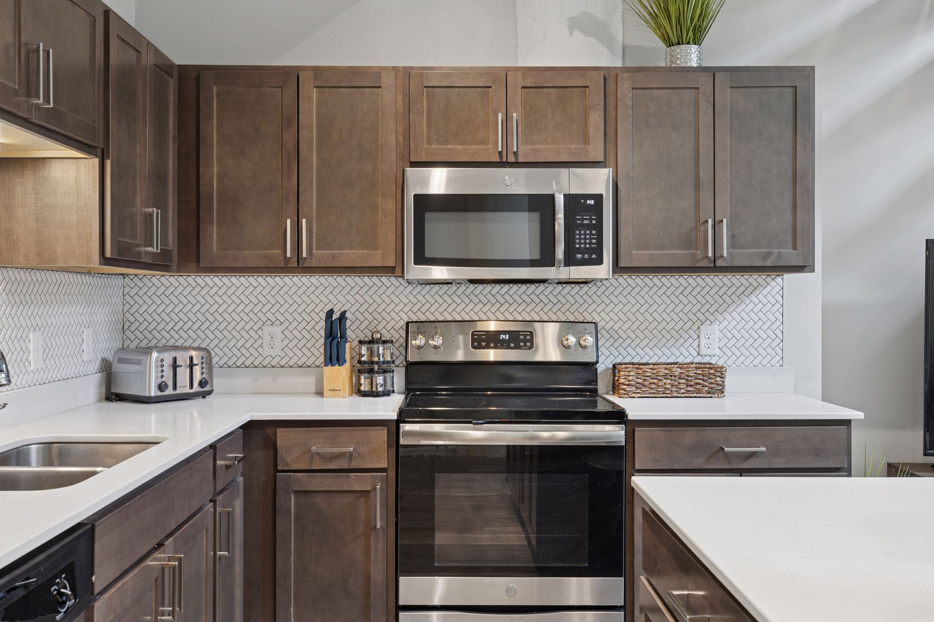 Kitchen with brown cabinets, stainless steel appliances, white countertops, and a mosaic backsplash.