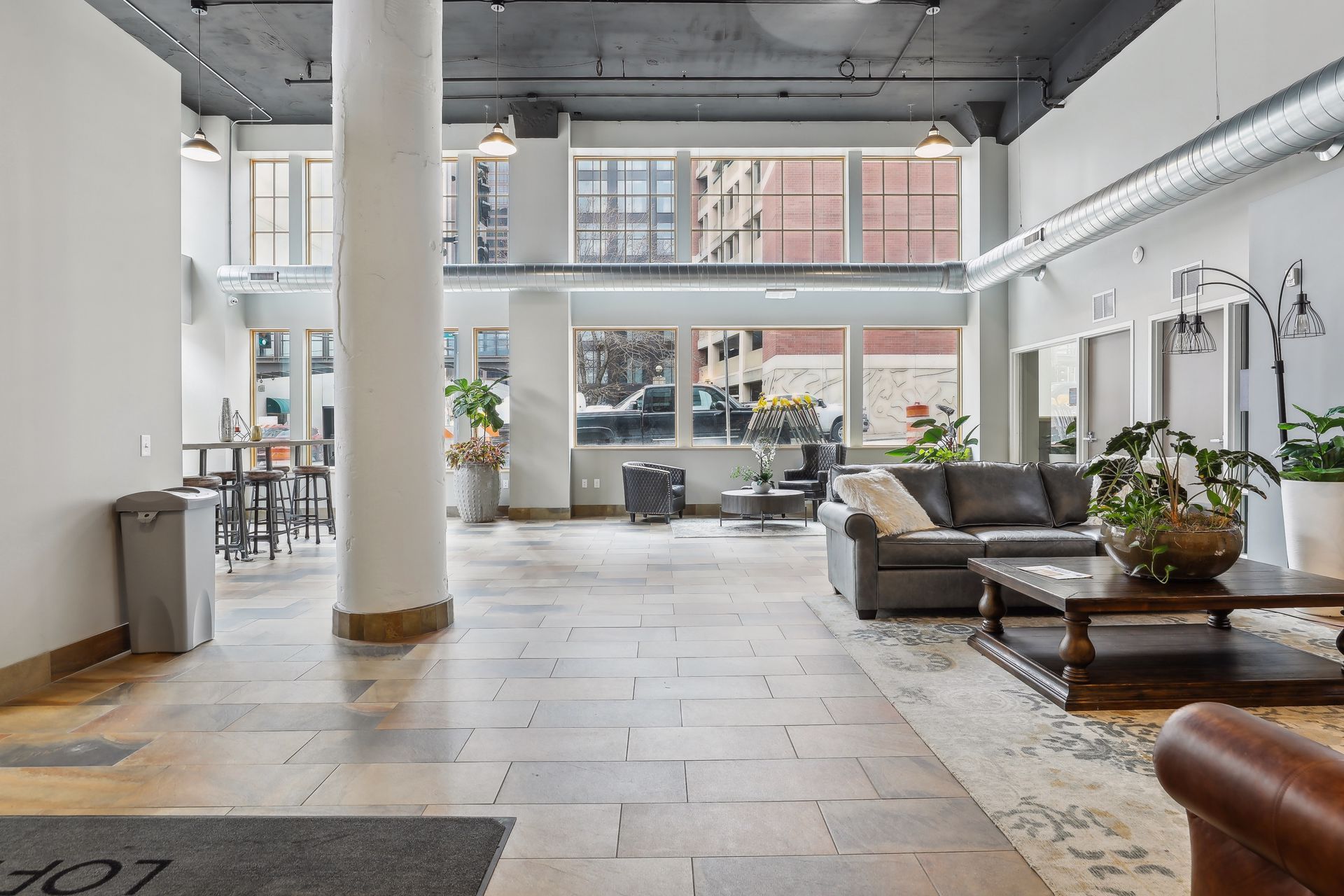 Spacious lobby with stone flooring, seating area, large windows, and a central pillar.