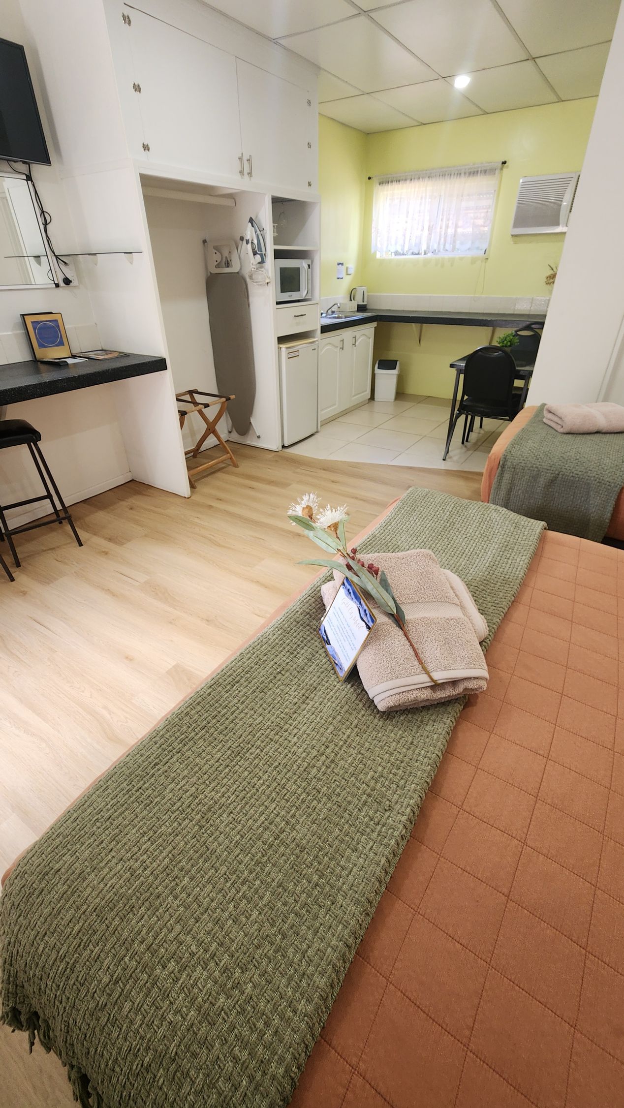 Two twin beds with coral bedding and green throws in a bright, minimalist bedroom.