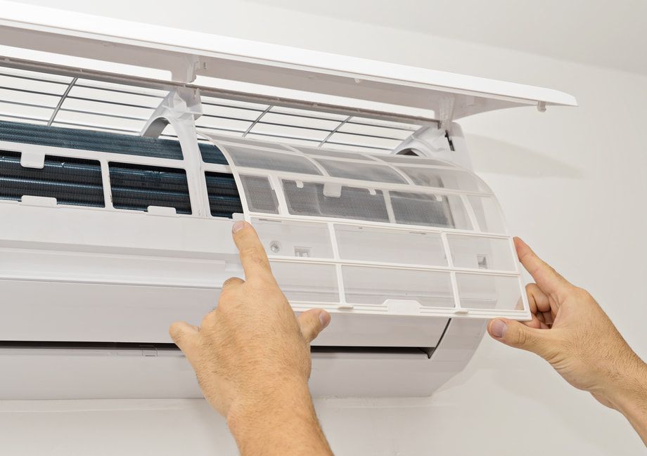A Person Is Cleaning An Air Conditioner With Their Hands — Ramm Air Conditioning In Port Macquarie, NSW